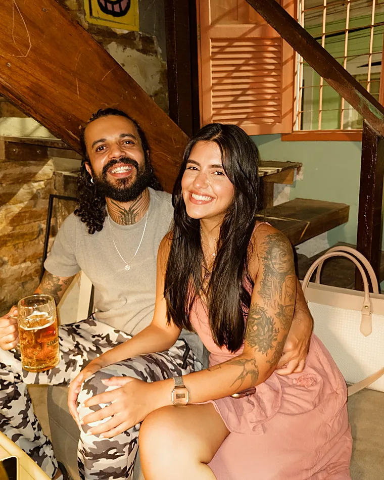 Casal sorrindo à mesa durante um encontro no Pitaco