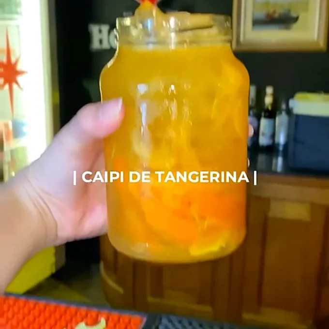 Caipirinha de tangerina servida em caneca de vidro no balcão