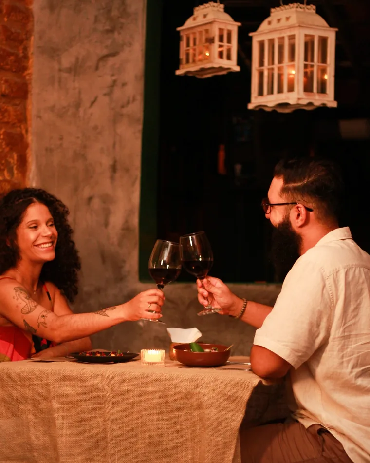 Casal brindando com vinho à luz das lanternas no quintal do Pitaco