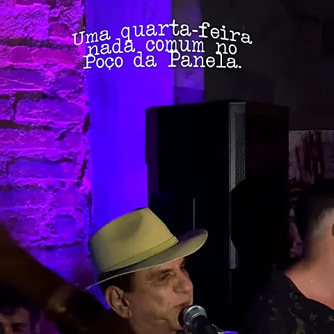 Cantor de chapéu se apresentando ao microfone no quintal