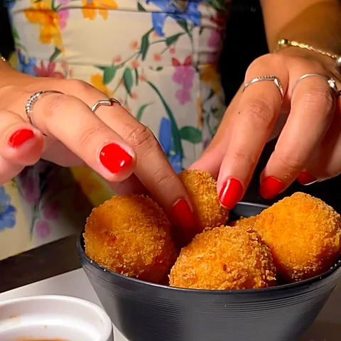 Croquetas de cupim sendo servidas com molho
