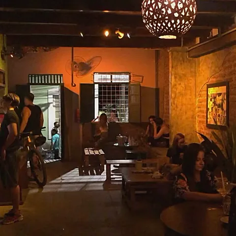 Salão interno do Pitaco com luminária pendente e meia-luz