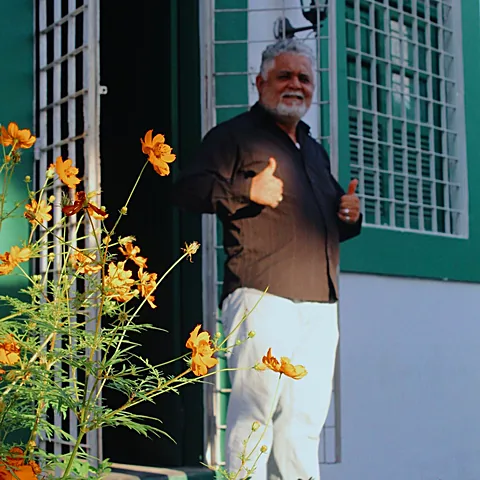 Porta verde da casa com flores amarelas no jardim